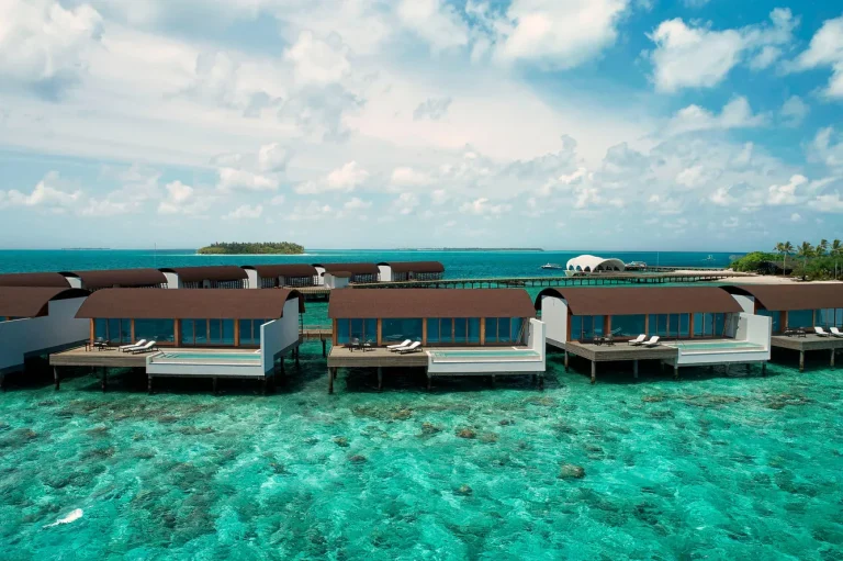 Row of overwater villas with private pools above clear turquoise reef water at The Westin Maldives Miriandhoo Resort, Baa Atoll