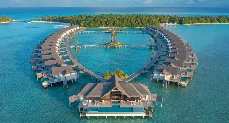 Aerial view of two curved jetties of water pool villas meeting at a central pavilion at Niyama Private Islands, Dhaalu Atoll, Maldives