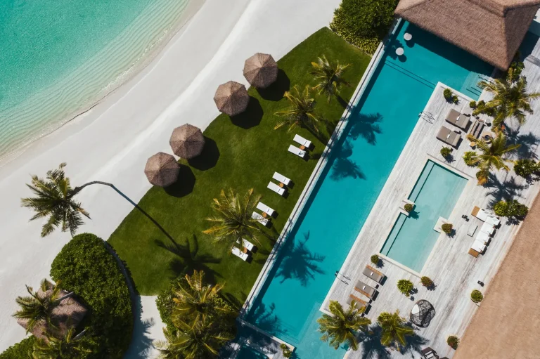 Aerial view of the long pool, lawn and beach cabanas on Ithaafushi Private Island at Waldorf Astoria Maldives Ithaafushi, South MalΓ© Atoll