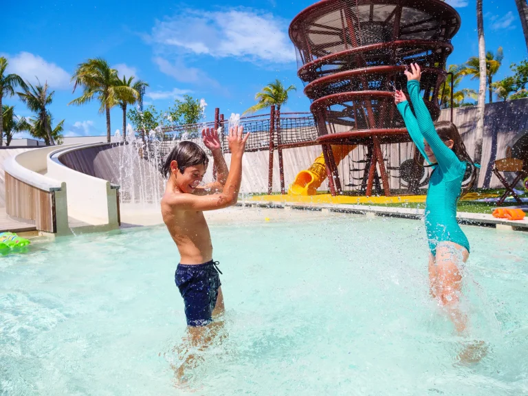 Children splashing in a pool beside a spiral play tower and slide at Ritz Kids, The Ritz-Carlton Maldives, Fari Islands