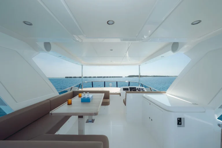 Shaded upper deck with a dining table, seating and views across the lagoon, The Ritz-Carlton Maldives yacht