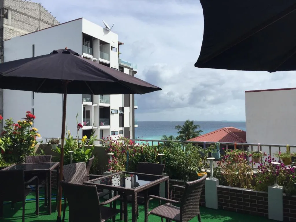 Rooftop terrace with dining tables and umbrellas at Rosemary Boutique, Maafushi, Maldives