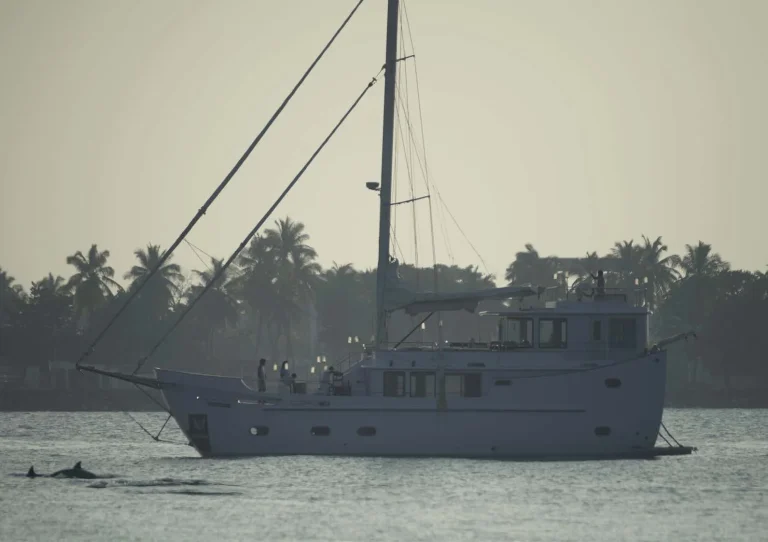 Two-masted yacht at anchor in a calm lagoon with palms behind, Soneva in Aqua, Maldives