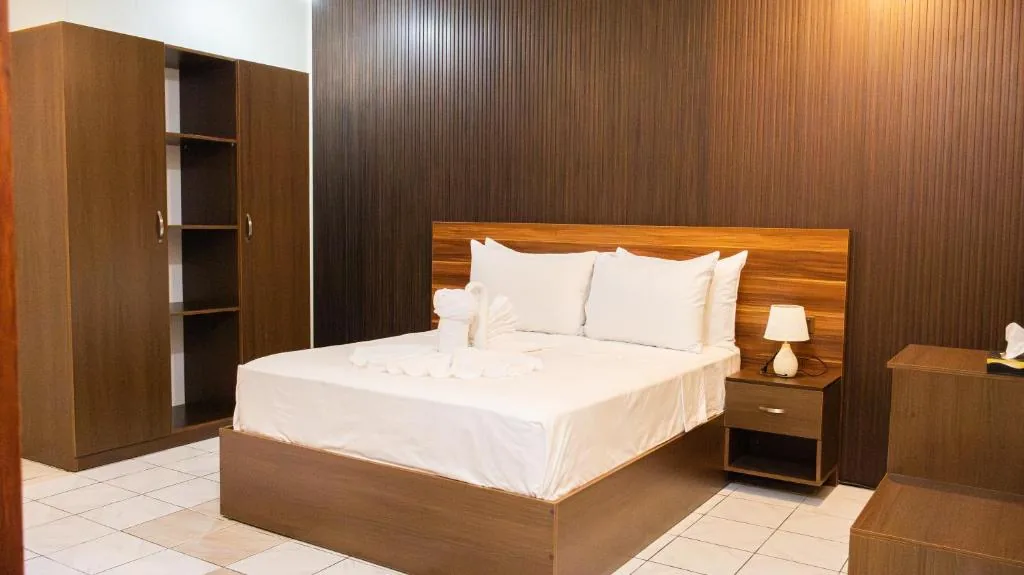 Bedroom with a large bed with a wooden headboard at Valhali Guesthouse, Huraa, Maldives