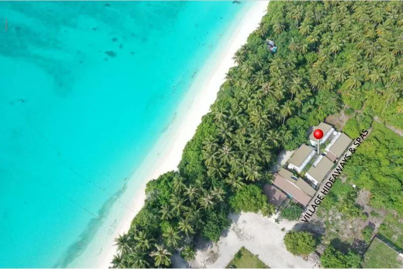 Aerial view of a palm-fringed white-sand beach with turquoise lagoon and red 'Village Hideaways & Spas' marker at Village Hideaways & Spas, Fulhadhoo, Maldives